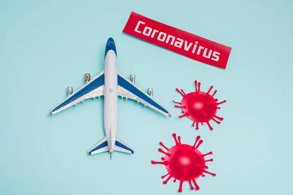 Top view of toy near card with coronavirus lettering and decorative coronavirus molecules on blue — Stock Photo