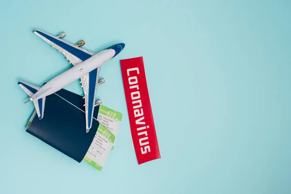 Top view of toy near card with coronavirus lettering and passports with air tickets on blue — Stock Photo