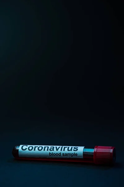 Test tube with coronavirus blood sample on dark background — Stock Photo