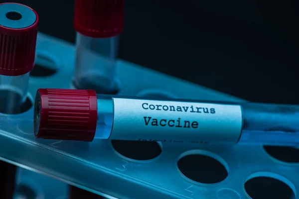 Support pour éprouvettes avec vaccin contre le coronavirus sur fond sombre — Photo de stock