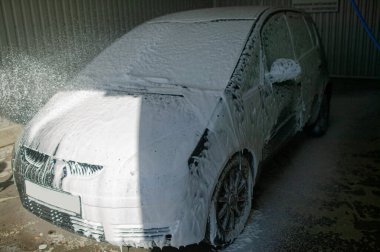 Oto yıkamada araba yıkayan, oto yıkama istasyonunda arabasını yıkayan genç bir adam..