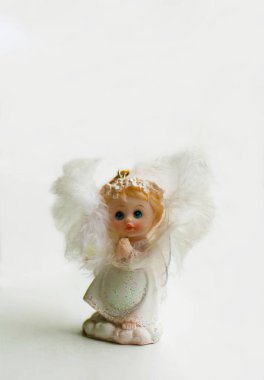 Beyaz, küçük, güzel bir melek. Beyaz bir arka planda seramik bir figür..