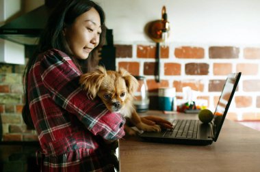 Neşeli Sahibi 'nin yanında oturan Köpek Evde Dizüstü bilgisayar kullanıyor.