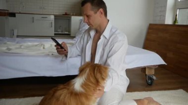 Genç adam evde evcil köpekle oynuyor.