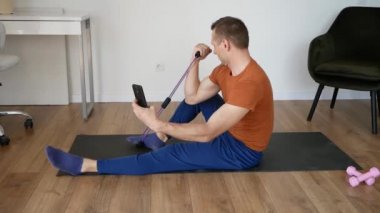 Evde cep telefonu kullanan bir adam spor sahasında yatıyor..