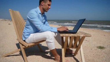 İşadamı laptopuyla tropik plajda çalışıyor..