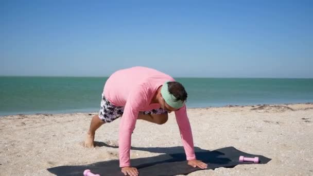 粉红中有趣的年轻人在海滩上做体育锻炼 — 图库视频影像