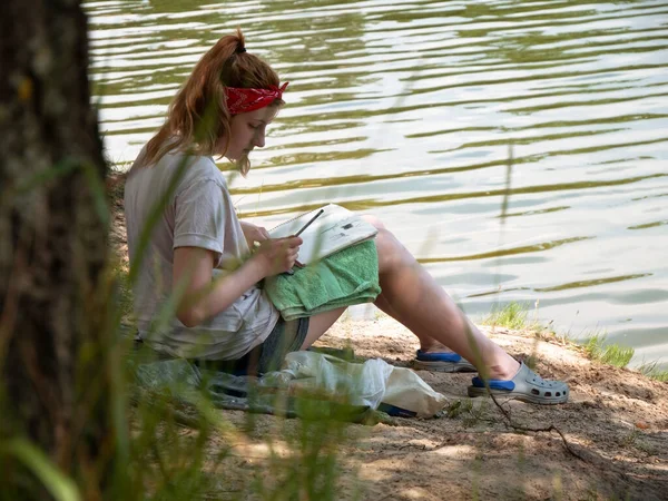 Girl Writer Draws School Park Under A Big Tree Near Lake.