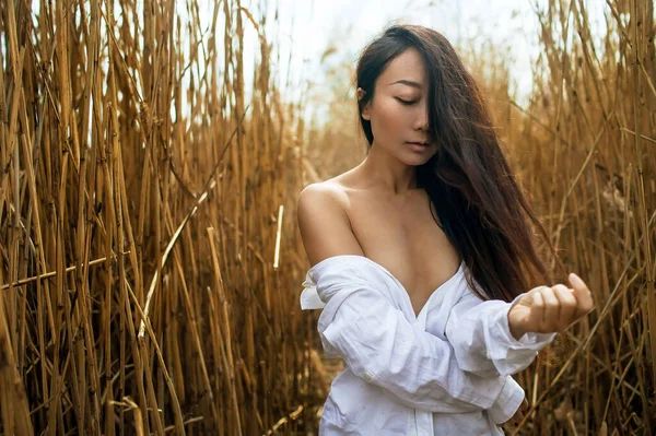川で乾いた葦の上のセクシーなアジア人女性 — ストック写真