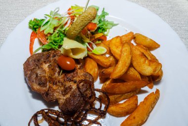 Baharat ve taze otlar taze domates, kızarmış patates ve kırmızı sıcak Chili Peppers ile deneyimli ızgara T-kemik biftek