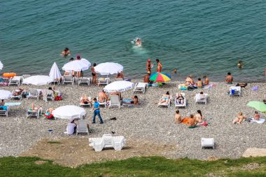 Batum, Georgia-Temmuz 2015 turist mavi gökyüzü ile Batum içinde çakıl sahilde sunning 3