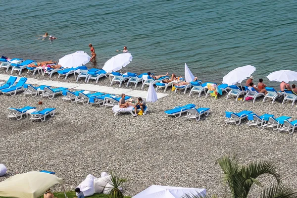 Batum, Georgia-Temmuz 2015 turist mavi gökyüzü ile Batum içinde çakıl sahilde sunning 3