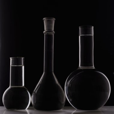 Laboratuar donanımları, üç cam şişesi siyah arka plan üzerine