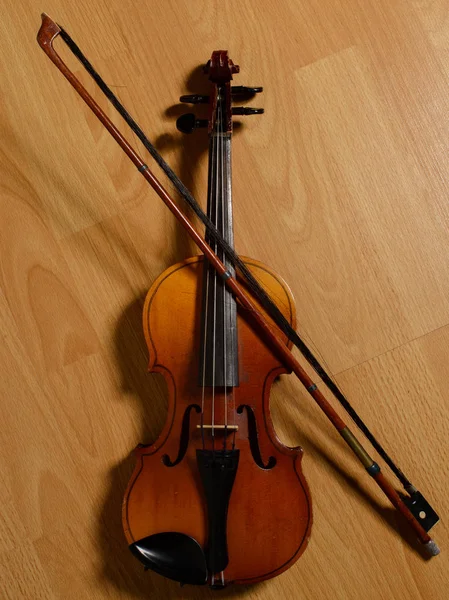 Velho violino e arco quebrado deitado no chão de madeira — Fotografia de Stock