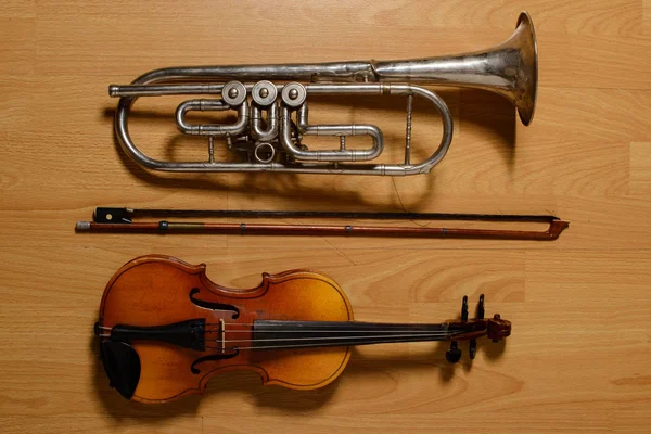 Trombeta e violino quebrados no chão de madeira — Fotografia de Stock