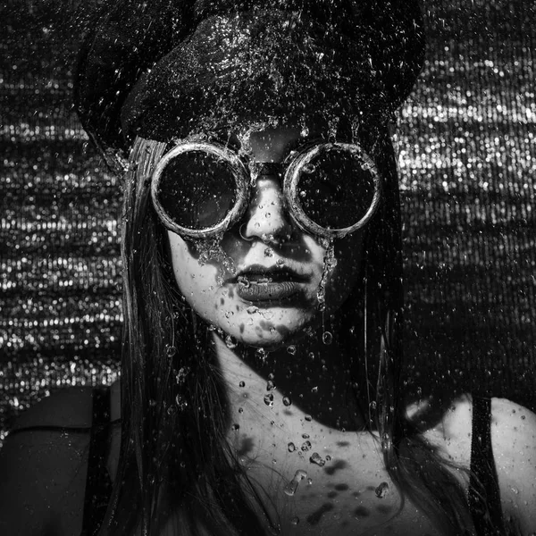 Strong girl with glasses and cap standing in the shower — Stockfoto