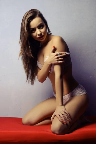 Jovem menina atraente em lingerie branca no sofá vermelho — Fotografia de Stock