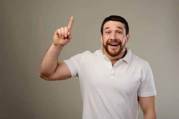 Jonge man heeft idee, wijzen met de vinger omhoog geïsoleerd op grijze achtergrond. — Stockfoto