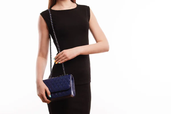 Attraente ragazza in abito nero in piedi con borsa blu isolato su bianco — Foto Stock
