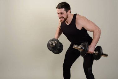 Genç bir atlet bir egzersiz dumbbells ile omuz kaslarının gelişimi üzerinde gerçekleştirir.