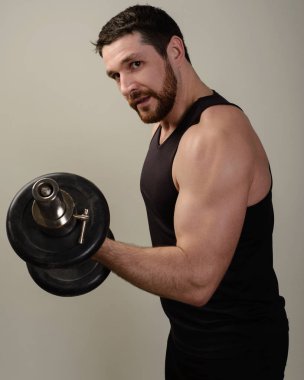 Pazı performans spor salonunda genç atlet Dumbbells ile bukleler