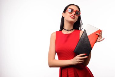 Kırmızı elbiseli çekici kız ve bir kalp şeklinde giyen güneş gözlüğü çok renkli bir debriyaj onun elinde tutan