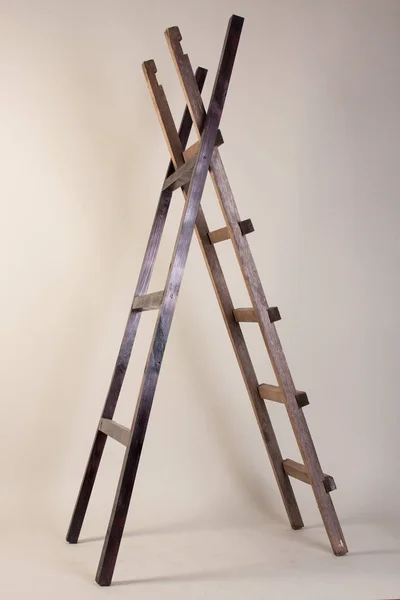 Two wooden ladders on a gray background