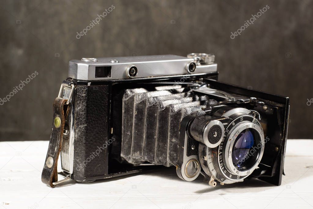 Old vintage camera on white wooden table black background
