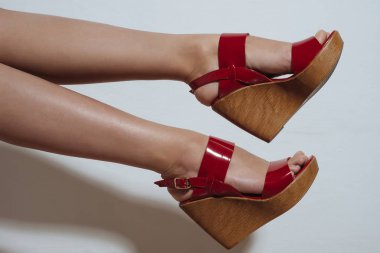 Güzel kadın bacaklarını açıp bir kama üzerinde kırmızı sandalet