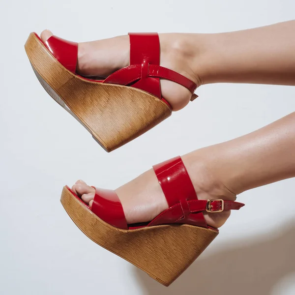 Beautiful female legs in red sandals on a wedge