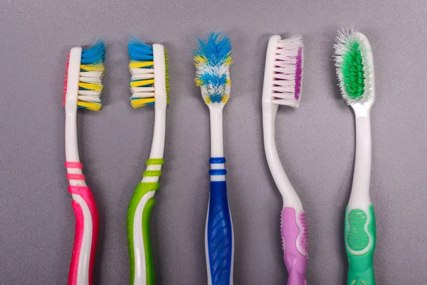 Old colorful toothbrushes on gray background. — Stock Photo, Image