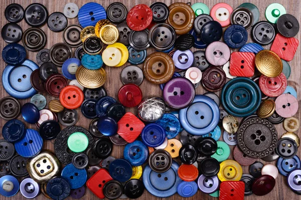 Old multi-colored buttons scattered on a wooden background — Stock Photo, Image