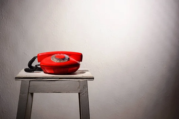 Telefone vintage vermelho em um banquinho branco — Fotografia de Stock