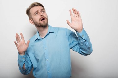 Mavi tişörtlü şık adam uzakta sürpriz kaldırdı elleriyle görünüyor.