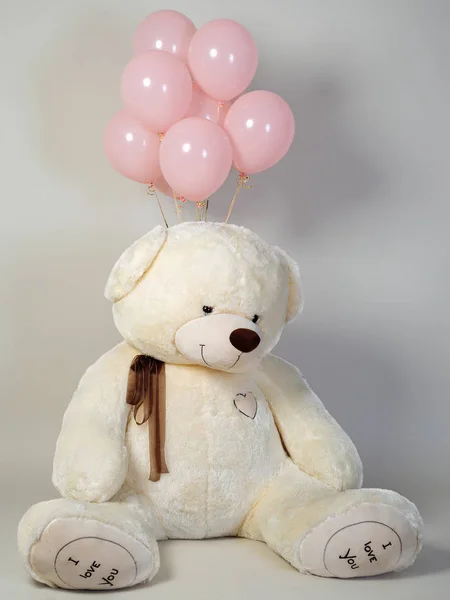 big teddy bear with pink balls.A toy is a Christmas present.