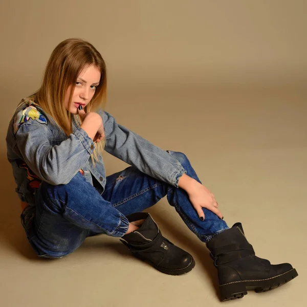 Hipster dziewczyna siedzi na podłodze przed graybackground. — Zdjęcie stockowe