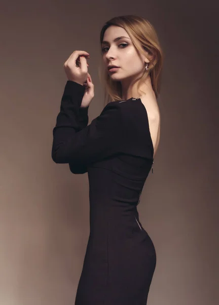 Schöne junge Frau in schwarzem Kleid mit langen lockigen Haaren posiert im Studio — Stockfoto