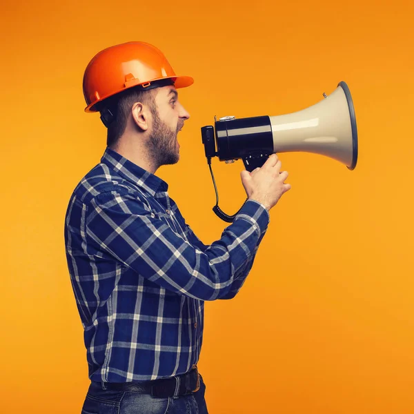 Angry worker man with a megaphone on yellow background