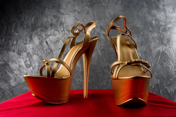 golden strip high heels on red satin background