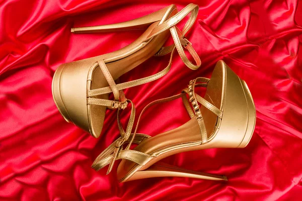 golden strip high heels on red satin background