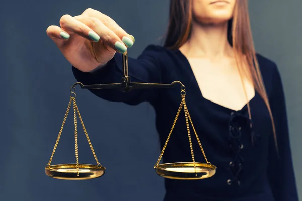 Serious woman holding the justice scale on dark background