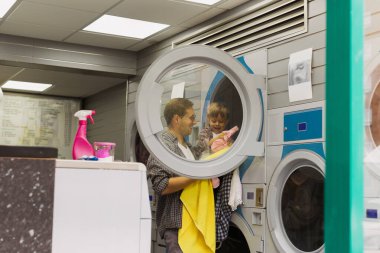 Baba oğluna çamaşır yıkamayı öğretiyor.