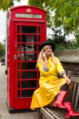 Londra 'daki telefon kulübesinin yanında cep telefonu kullanan bir kız.