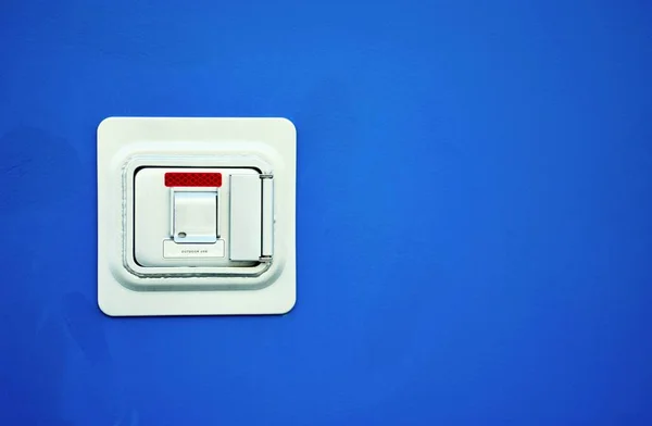 Lock box on a blue wall. It is for external storing of keys, access cards and other vital items for a business if emergency services need quick access to the premises.