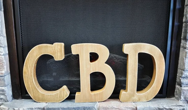 CBD sign made from wood in front of a fireplace on display, framed by brickwork. Medical CBD is a fast growing industry after the legalization of cannabis in many places worldwide.