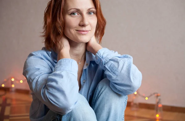 smiling girl sitting on floor in a blouse and jeans