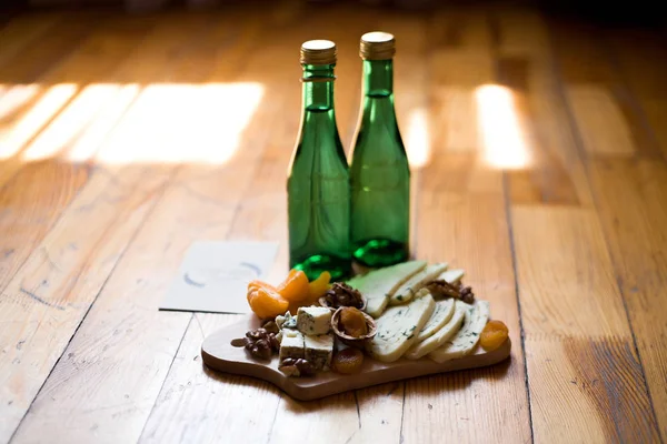 Queso, nueces, albaricoques secos, mandarinas y dos botellas de agua en el suelo de madera —  Fotos de Stock