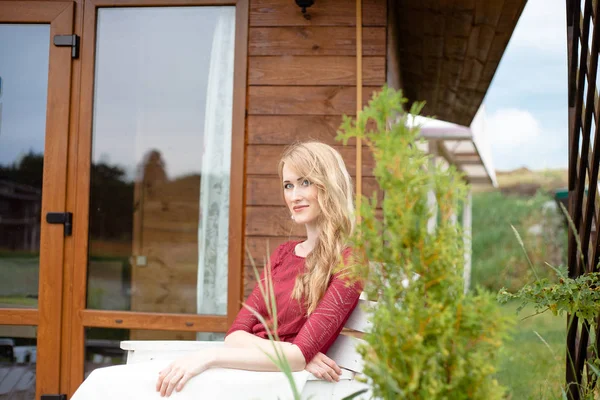 Piękna panna młoda siedzi obok dom drewniany — Zdjęcie stockowe