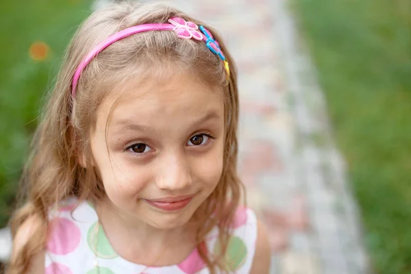 Słodkie mała dziewczynka uśmiecha się w parku zbliżenie — Zdjęcie stockowe