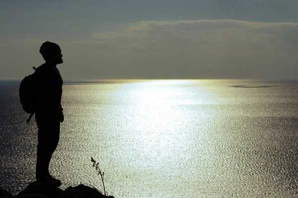 바위에 서 있는 바다에서 보고 하는 남자의 실루엣 — 스톡 사진